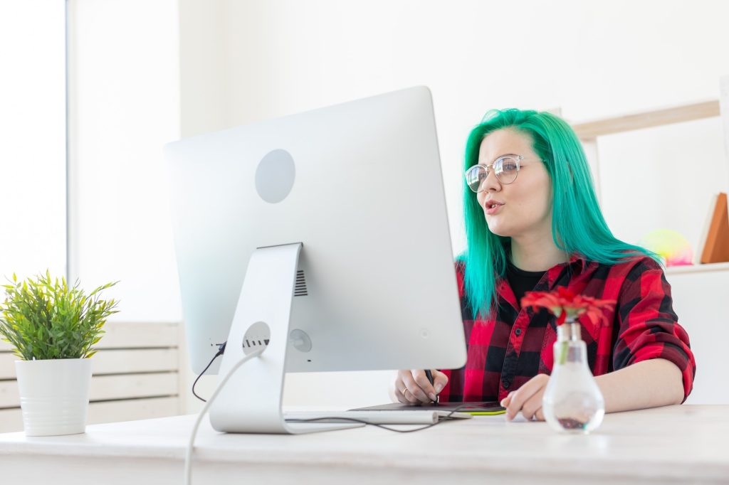 Illustrator, creative, web design concept - Female graphic designer with green hair at work